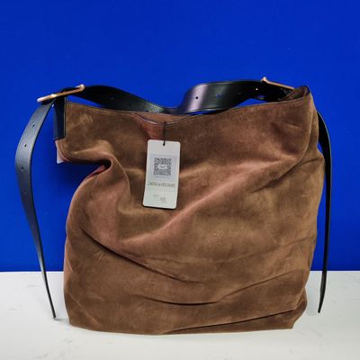 Le grand sac marron est posé sur la table, avec un mur bleu en arrière-plan.