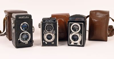 several old cameras are lined up in a row on a white surface