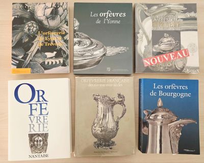 quatre livres posés sur une table sur laquelle se trouve un vase en argent