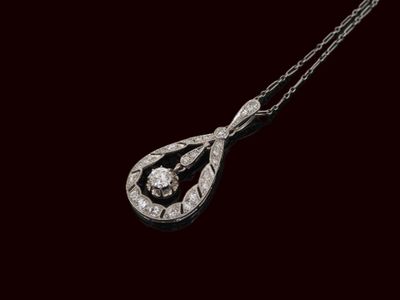 un vieux pendentif en diamant taillé, suspendu à une chaîne, sur fond noir