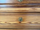 a close up of a wooden dresser with brass knobs