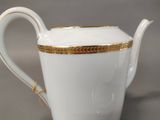a white tea pot with gold trim on it
