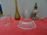 une table sur laquelle se trouvent un vase, un verre et une lampe