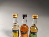 three miniature bottles of alcohol sitting next to each other on a table