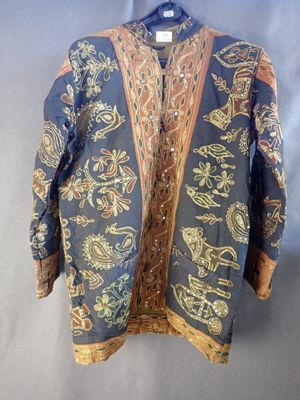 une veste bleue ornée de motifs dorés et rouges, suspendue à un cintre