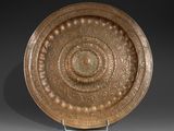 une grande plaque en bronze ornée d'un motif circulaire, posée sur un socle