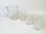 quatre verres et un pichet posés sur une table