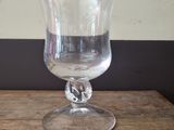 a clear glass on a wooden table with a white wall in the background