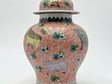 a pink and green vase with a lid sitting on a white surface