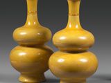 deux vases jaunes posés l'un à côté de l'autre sur une surface grise