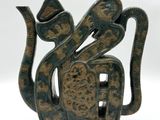 une sculpture représentant un serpent, de couleur verte et marron, posée sur une surface blanche