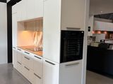 une grande cuisine avec des placards blancs et des plans de travail noirs
