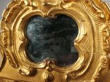 a gold clock with a mirror in the middle of it