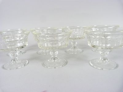 four clear glass goblets sitting on top of a white table