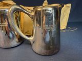 two silver pitchers sitting next to each other on a table