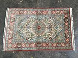 un tapis posé à même le sol, orné d'une bordure verte et rouge
