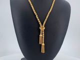 a gold chain necklace with a tassel on a mannequin