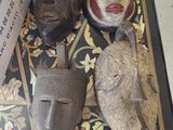 trois masques posés par terre à côté d'un panneau