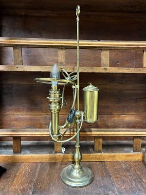 une lampe en laiton posée sur une étagère en bois