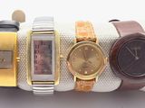 four different watches on a white cloth with gold and silver bands