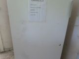 un réfrigérateur blanc dans une pièce sale, sur lequel est accrochée une affiche