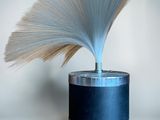 a blue vase with a white fan on top of it