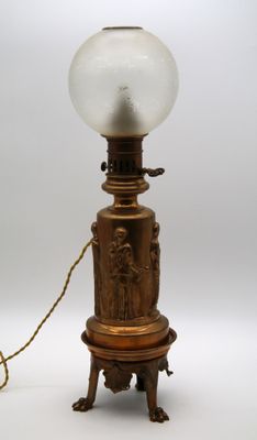 une lampe ancienne en laiton surmontée d'un globe en verre