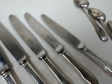 a lot of silver spoons and knives on the table