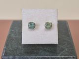 a close up of a pair of green earrings on a white card