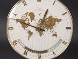 une image représentant une horloge dorée et blanche sur laquelle figure une carte du monde