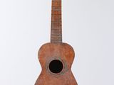 a wooden guitar hanging from a string on a wall