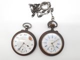 deux vieilles montres de poche posées l'une à côté de l'autre sur une surface blanche