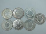 six types différents de pièces d'argent sur une surface blanche