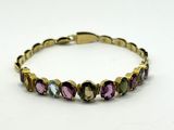 un bracelet en or avec des pierres multicolores sur fond blanc