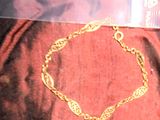 une photo d'un bracelet en or posé sur un tissu rouge