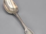 silver plated spoon on a gray surface with a silver spoon in the middle