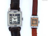 two watches sitting next to each other on a white surface