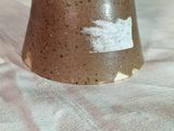 un vase marron posé sur une table recouverte d'une nappe blanche