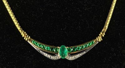 a close up of a necklace with a green stone on it