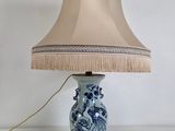 a blue and white lamp with a beige shade on it