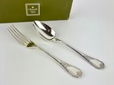 two forks and two spoons sitting next to a green box