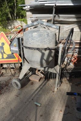 une bétonnière garée devant un bâtiment, à côté d'un panneau de chantier