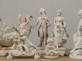 cinq figurines assises sur une table, dont l'une tient une fleur