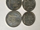 four different british coins sitting on top of a white surface