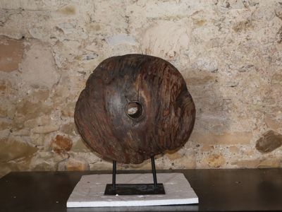 une sculpture représentant un disque en bois posé sur un socle