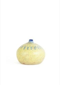 un vase jaune et bleu posé sur une surface blanche