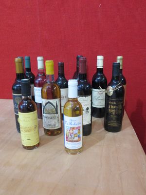 Des bouteilles de vin sont alignées sur une table devant un mur rouge.
