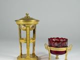 a gold and red vase next to a red bowl