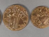 quatre médailles d'or de tailles et de formes différentes sur un fond blanc
