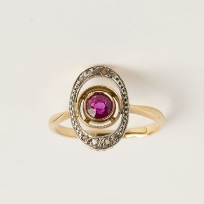 un gros plan d'une bague en or ornée d'une pierre rose au centre